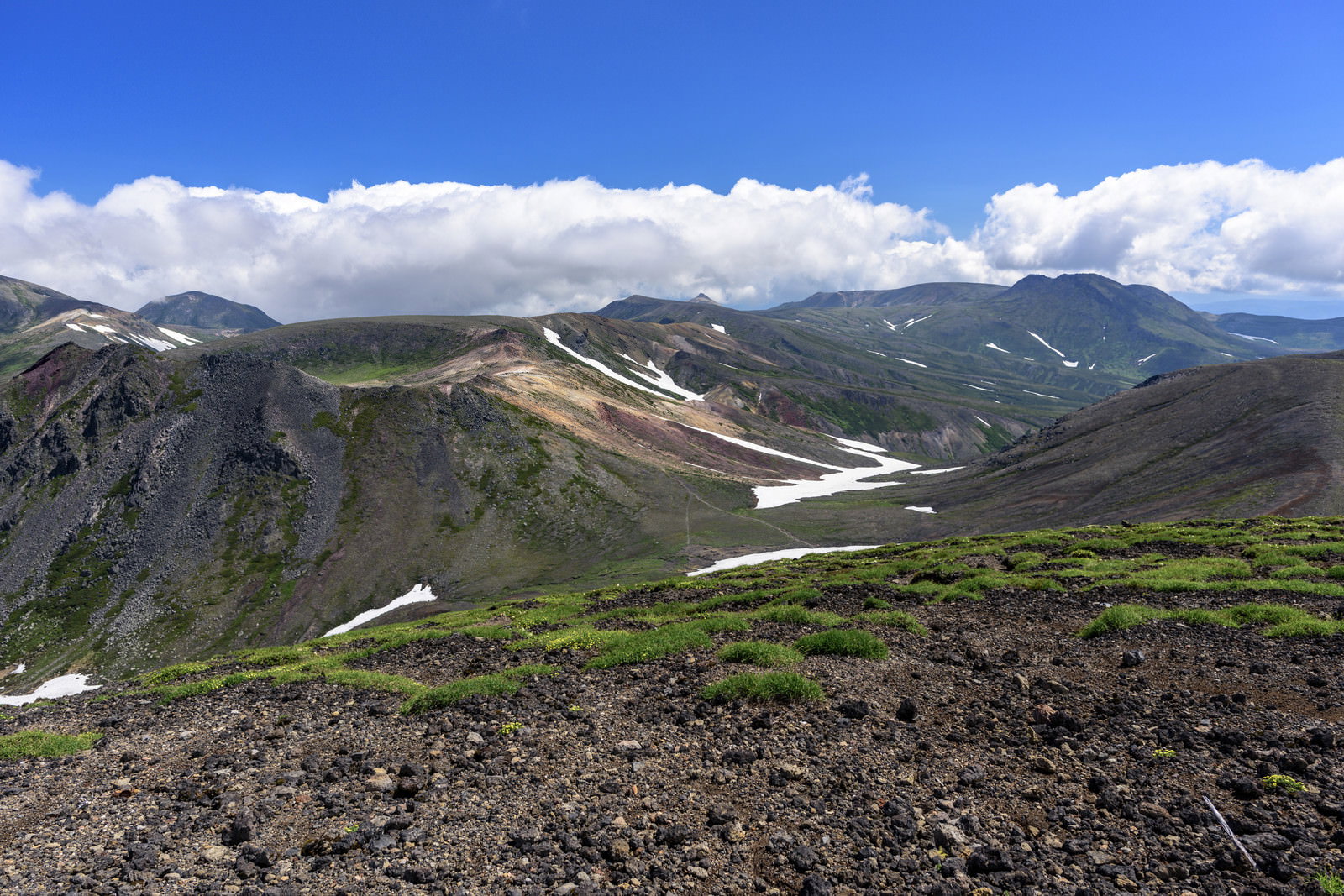 旭岳山頂から望む大雪山の山々と青空、残雪が点在する雄大な山岳風景