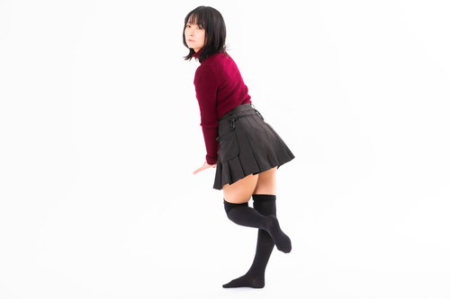 赤いトップスを着た女性が片足を上げて振り向くポーズ