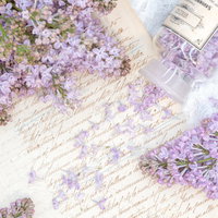 古い手紙の上に散らばったライラックの花とガラスボトルの写真