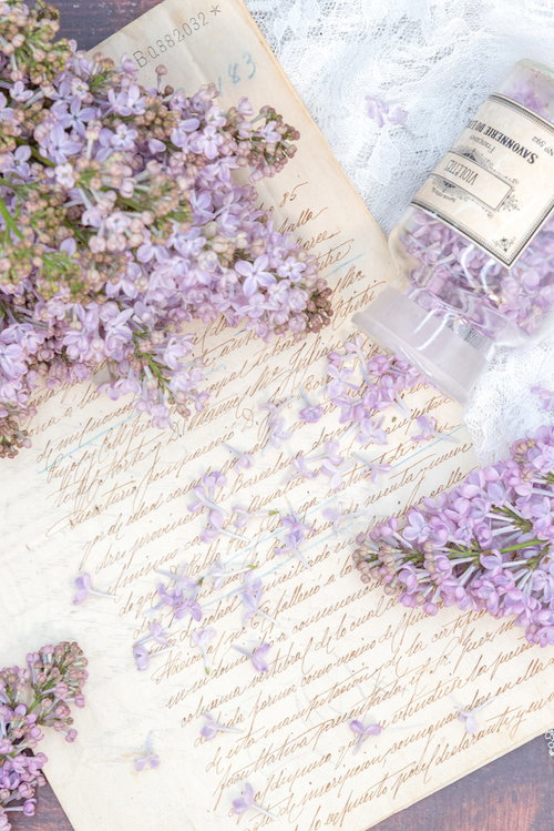 古い手紙の上に散らばったライラックの花とガラスボトル