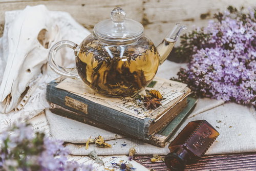 ハーブティーと洋書、紫色の小花が並ぶティータイム