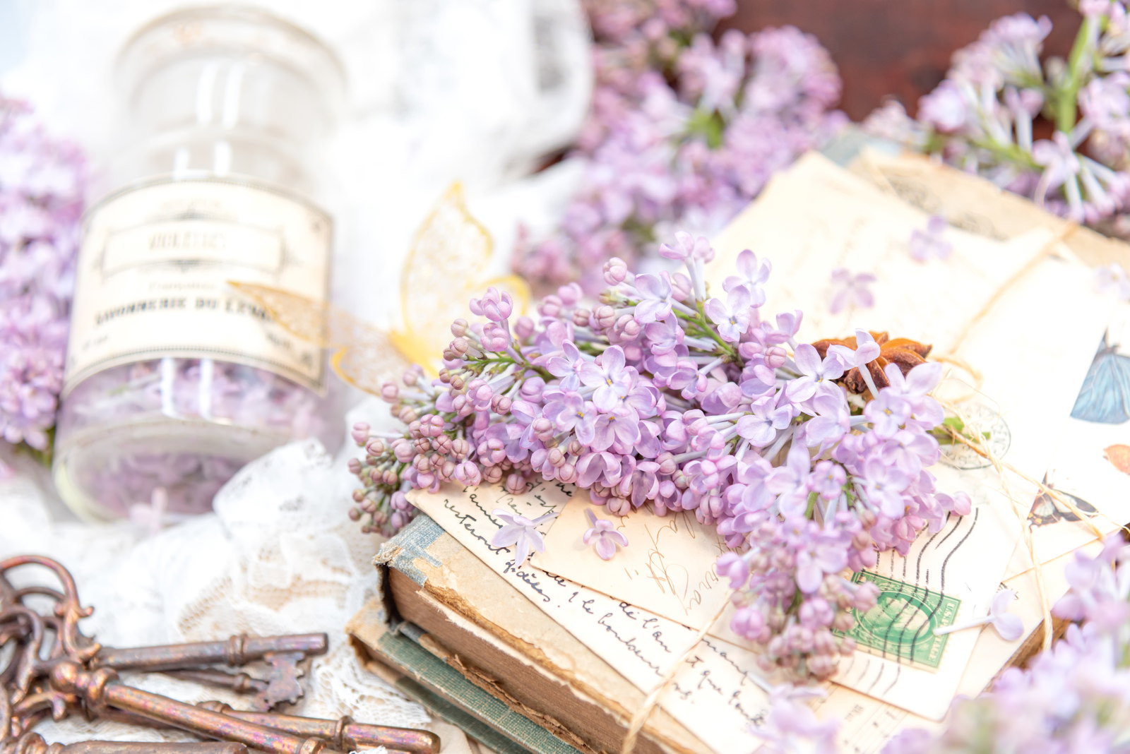 古い葉書と洋書の上に置かれた紫色のライラックの花
