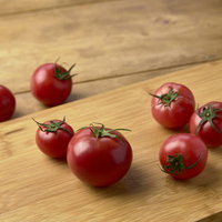 木製まな板の上に無造作に置かれたミニトマトの写真