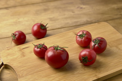 木製まな板の上に無造作に置かれたミニトマトの写真