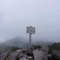 日光白根山山頂をガスが包む指導標の風景と岩場の写真