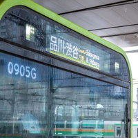 雨の中を走る山手線の緑色車両の窓の写真