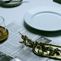 英文の新聞を広げたテーブルに置かれた白い食器類の写真