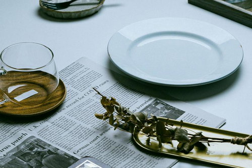 英文の新聞を広げたテーブルに置かれた白い食器類