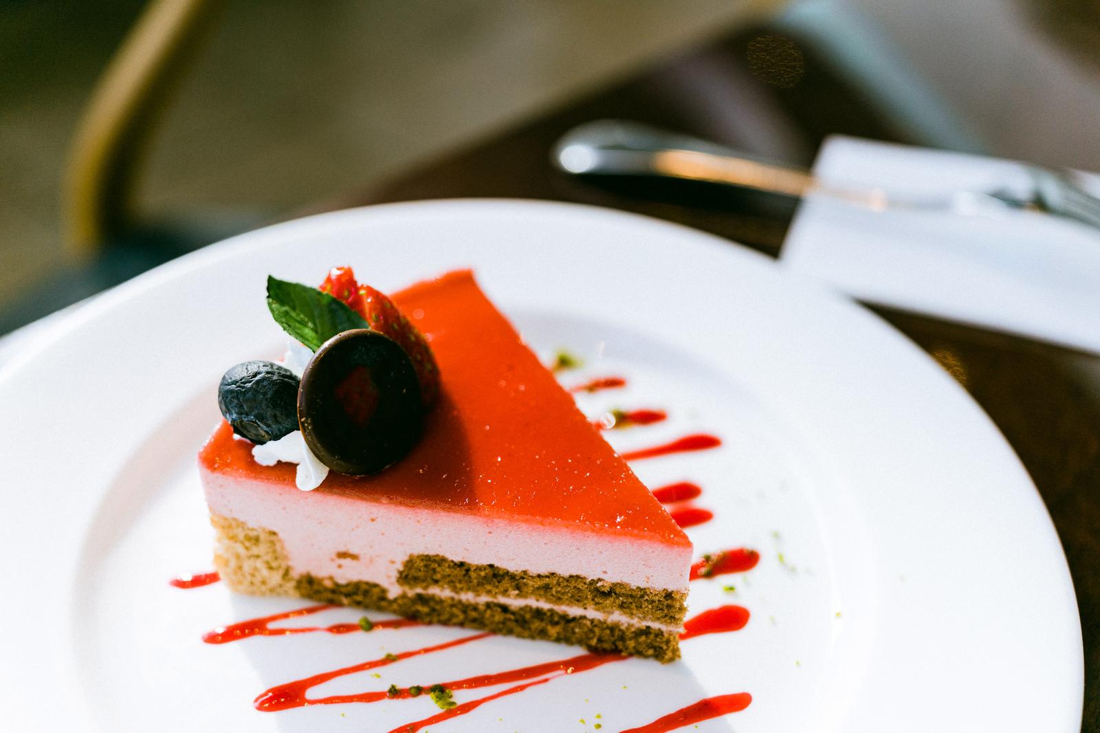 白い皿に盛られたピンク色クリームとオレンジゼリーのケーキ