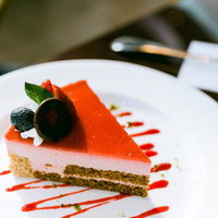 ピンク色のクリームとオレンジのゼリーが層状のケーキの写真