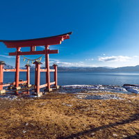 田沢湖畔に立つ朱色の鳥居とカメラマン（秋田県仙北市）の写真