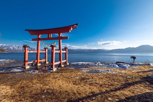 田沢湖畔に立つ朱色の鳥居とカメラマン（秋田県仙北市）