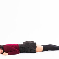 こっちを向いてうつ伏せする赤い服の女性のポーズの写真