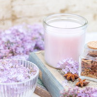 本の上に置かれたキャンドルとライラック、ガラスのグラスの写真