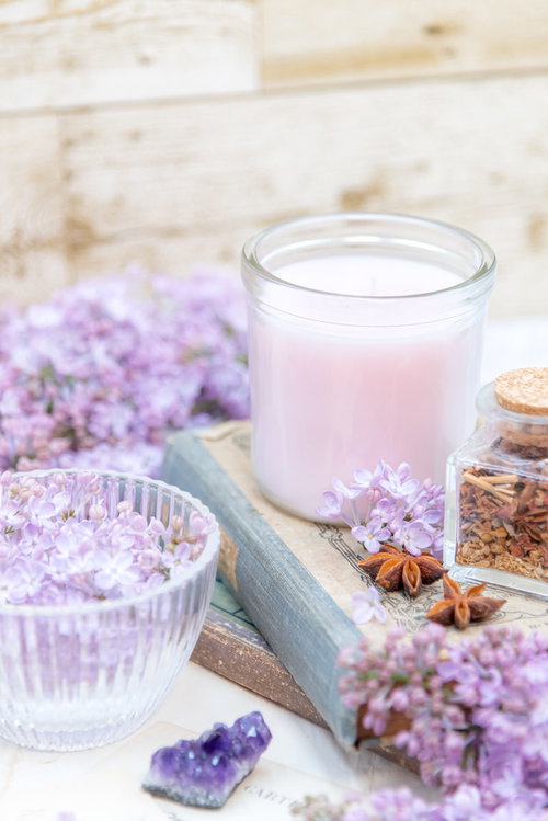 本の上に置かれたキャンドルとライラック、ガラスのグラス