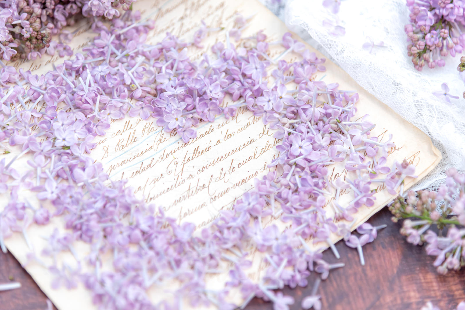 ライラックの花で作ったハート型の中に、手書きされたラブレターが置かれている