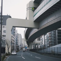 高速道路の高架下を通る一般道路と都市風景の写真