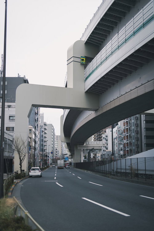 高速道路の高架下を通る一般道路と都市風景