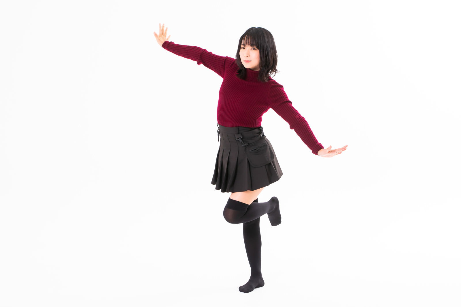 両手を広げて飛び立つようなポーズをする赤いセーター姿の女性［モデル：にゃるる］