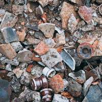 地面に散らばる割れた陶器の破片と廃棄物の写真