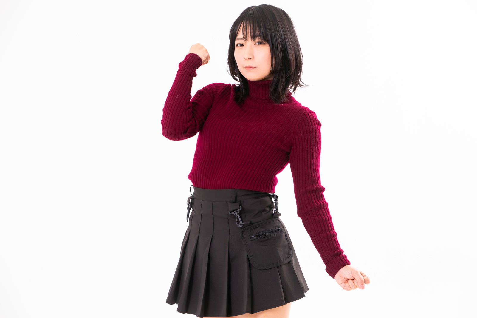 赤いニットと黒いスカートを着た女性がガッツポーズを決めている［モデル：にゃるる］