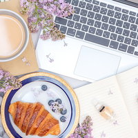 ライラックの花が映えるデスク周りとMacbookの写真