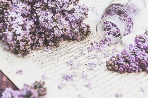 ガラス瓶からこぼれるライラックの花と手紙