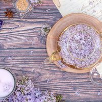 ライラックの花を浮かべたティーポットとハーブティーの写真