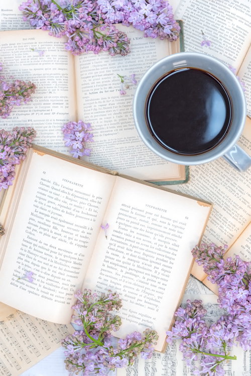 コーヒーカップと洋書に散らばるライラック