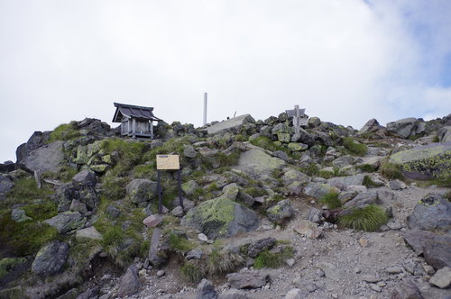 ガスで覆われた日光白根山山頂に建つ社と岩場の風景