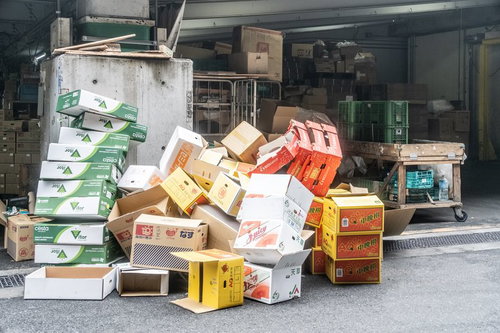 市場に乱雑に積み重ねられた段ボール箱と梱包材