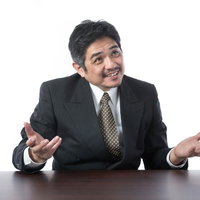 笑顔で説明するスーツ姿の年配上司の写真