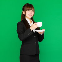 グリーンバックの前でコーヒーカップを持つビジネス女性の写真