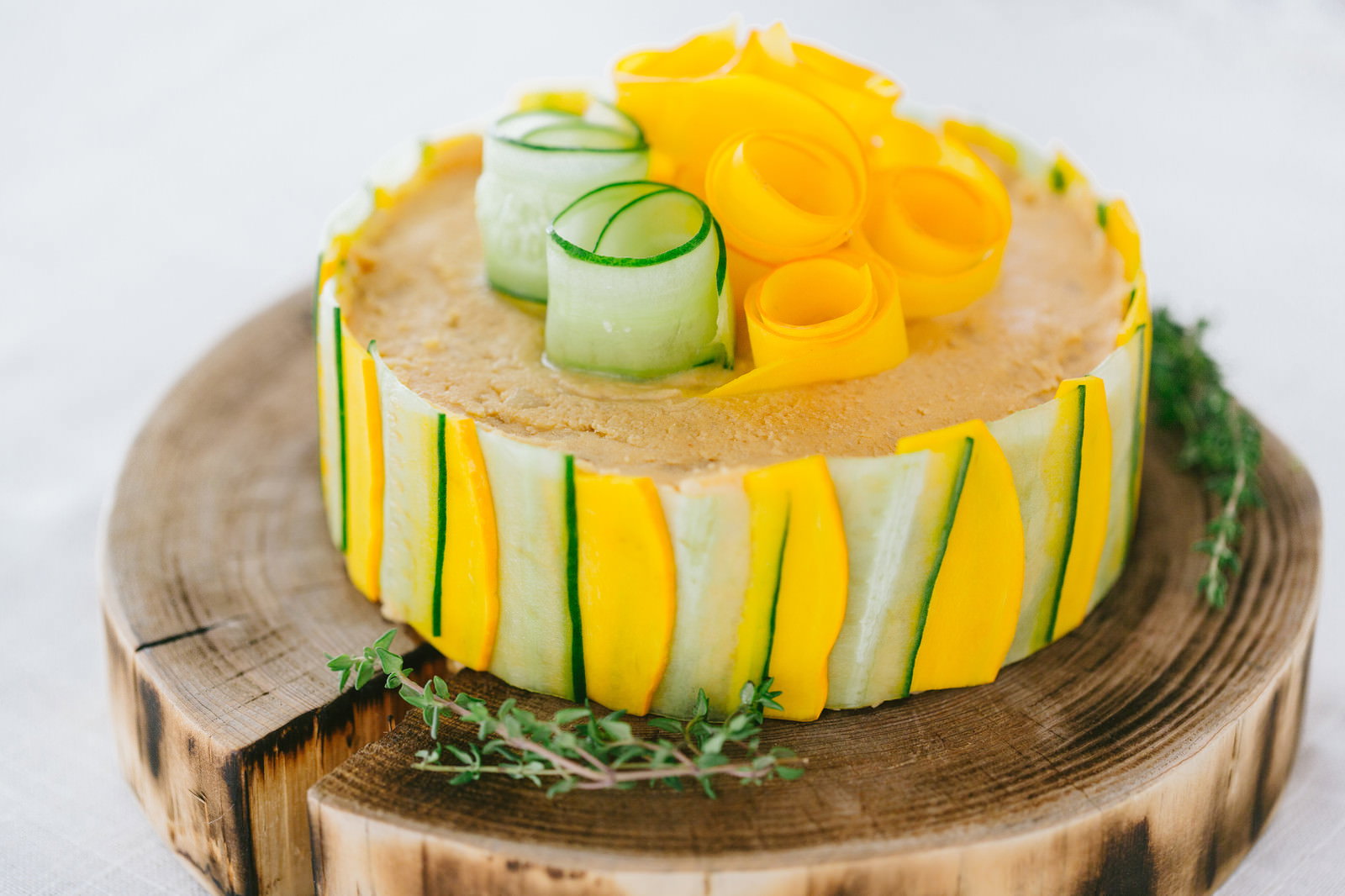 木製カッティングボードの上に置かれた、野菜スライスで装飾したクリームチーズケーキ