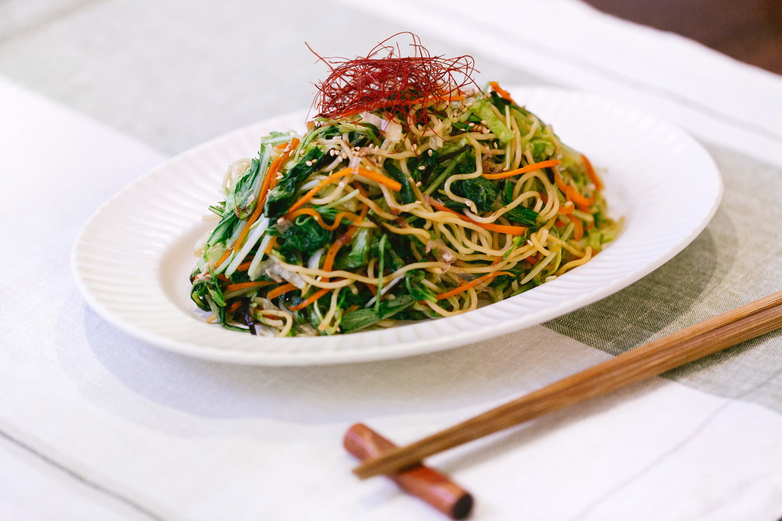 白い皿に盛った焼きそば。黄色い麺にニラ、もやし、ニンジンが混ざり、かいわれ大根をトッピング