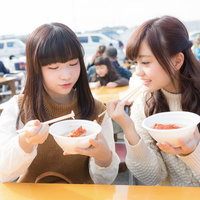 いすみ市の朝市フードコートで伊勢海老のお吸い物を食べる女性二人の写真