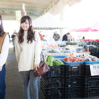 いすみ市の港の朝市で野菜を眺める女性観光客の写真