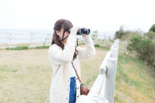 太東埼灯台の展望台で双眼鏡で景色を眺める女性