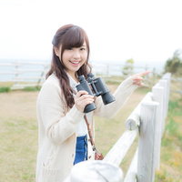 いすみ市の公園で双眼鏡を持ち笑顔で観光地を案内する女性の写真