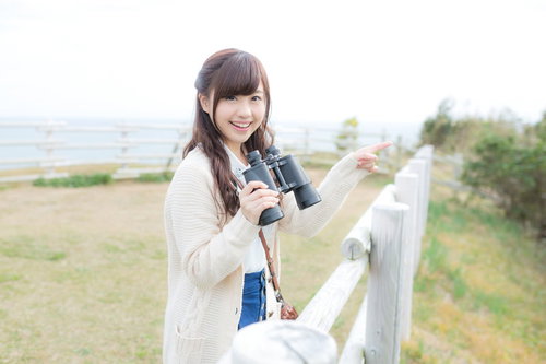 いすみ市の公園で双眼鏡を持ち笑顔で観光地を案内する女性