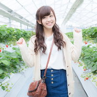 ビニールハウスのいちご狩りではしゃぐ女性の写真