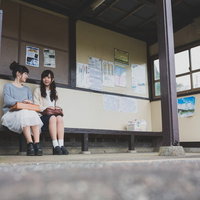 いすみ市の無人駅で電車の待ち時間に旅の思い出を共有する女性観光客の写真