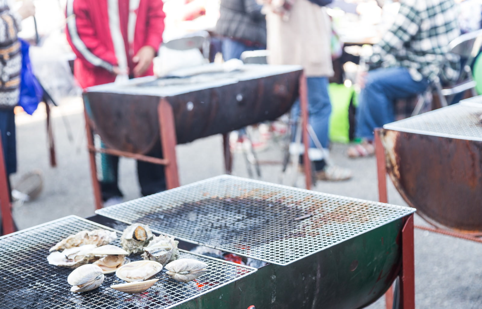 港の朝市で複数の人がテーブルを囲んで炭火焼きバーベキューをしている様子