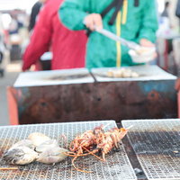 港の朝市で食べるハマグリと伊勢海老の網焼きの写真