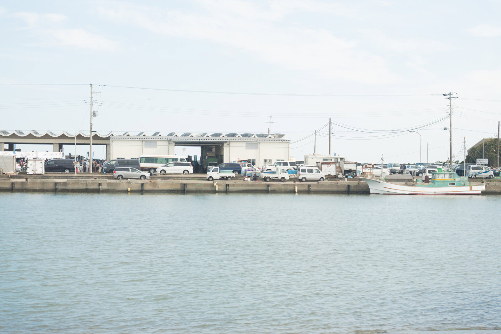 千葉県いすみ市の大原漁港で、防波堤に停泊する漁船と港の建物、駐車場の風景