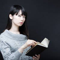 スマートフォンで読書する女性の写真