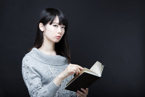 スマートフォンで読書する女性の写真