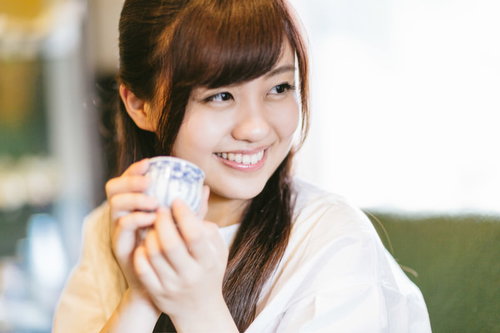 伊万里焼のおちょこで日本酒を飲む観光客の女性