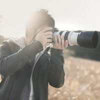 望遠レンズで風景を撮影する男性カメラマンの写真