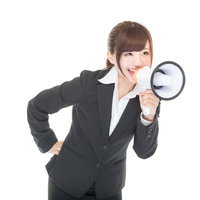 拡声器で大声を上げて応援する黒いスーツの女性社員の写真
